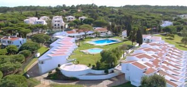An aerial view of a resort with multiple buildings, a swimming pool, and lush greenery. - Hotel Apartamento do Golfe (Loulé)