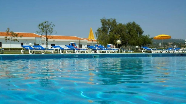 Piscina com água azul, rodeada por espreguiçadeiras e guarda-sóis.