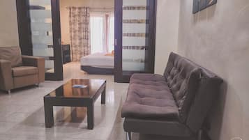 A living room with a sofa, a coffee table, and a chair. There is a sliding door leading to another room.
