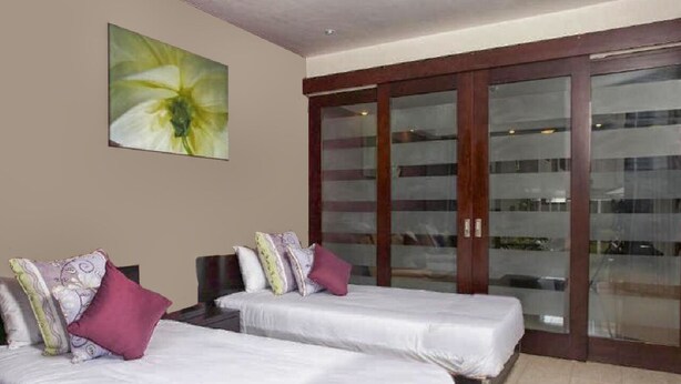 A hotel room with two beds, a large window, and a sliding glass door. - Grand Bay Suites (Grand-Baie)