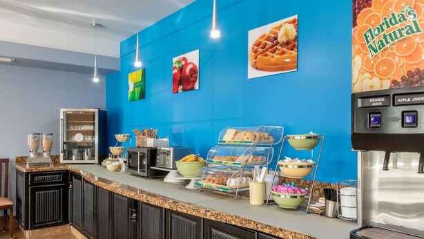A breakfast bar with various food items and a beverage dispenser. - Quality Inn & Suites at The Outlets Mercedes/Weslaco (Mercedes)