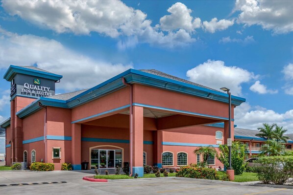 A hotel with a red facade and blue trim, featuring a sign that reads "Quality Inn & Suites."