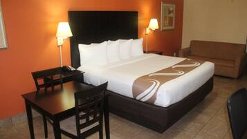 Una habitación de hotel con cama, escritorio, silla y sofá.