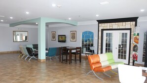 A reception area with a tiled floor, a reception desk, a waiting area with chairs, and a door leading to the kitchen. - Quality Inn & Suites at The Outlets Mercedes/Weslaco (Mercedes)