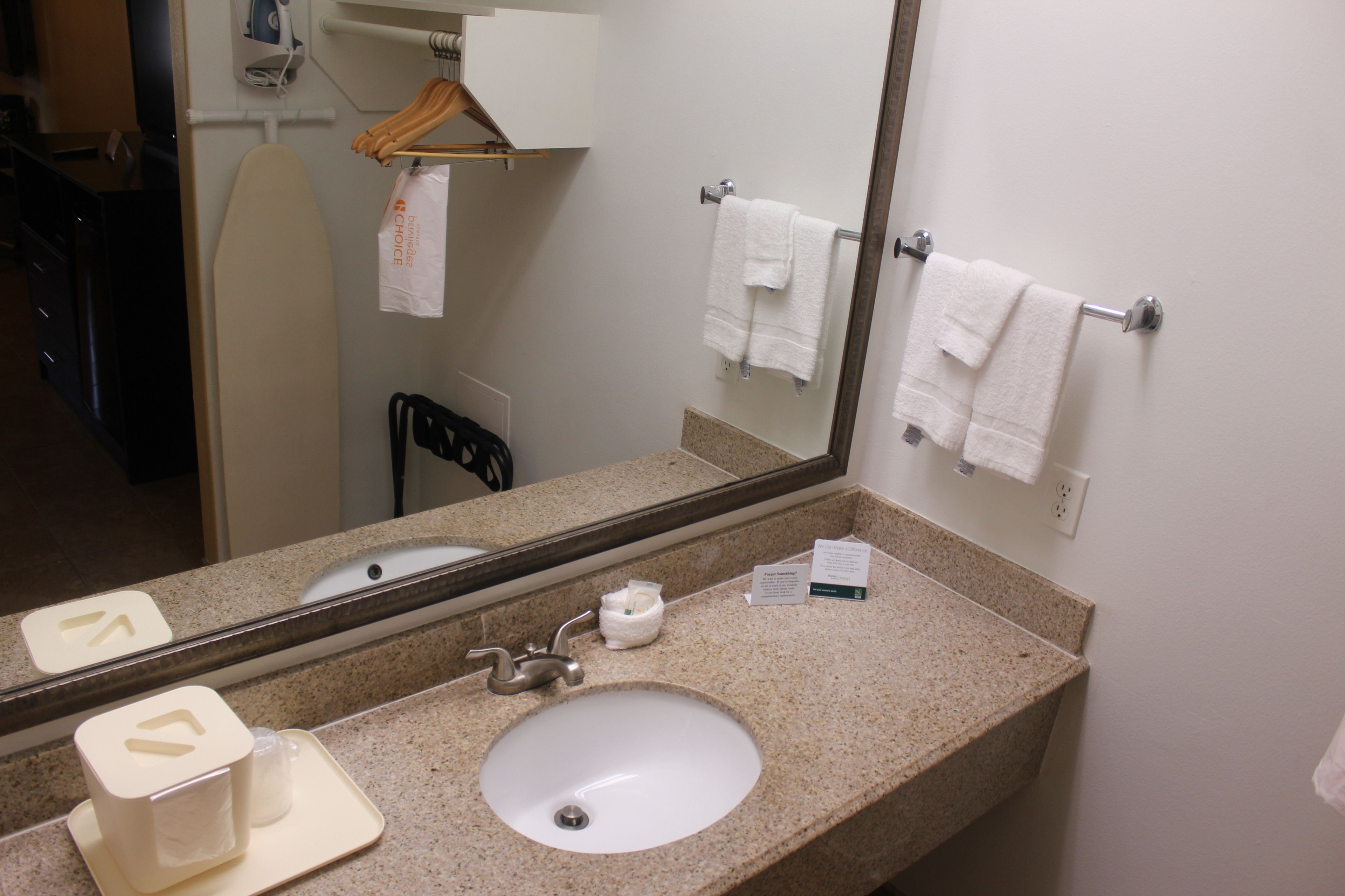 A bathroom with a sink, mirror, towel rack, and a hanging shower curtain rod.