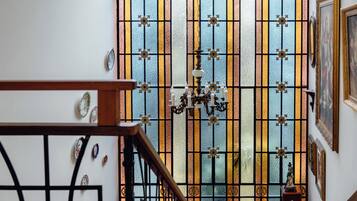 A staircase with a wooden handrail and black balusters, leading to a room with a large stained glass door.