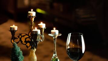 Un tavolo apparecchiato con un'insalata in una ciotola, un bicchiere da vino e un candelabro con candele accese.