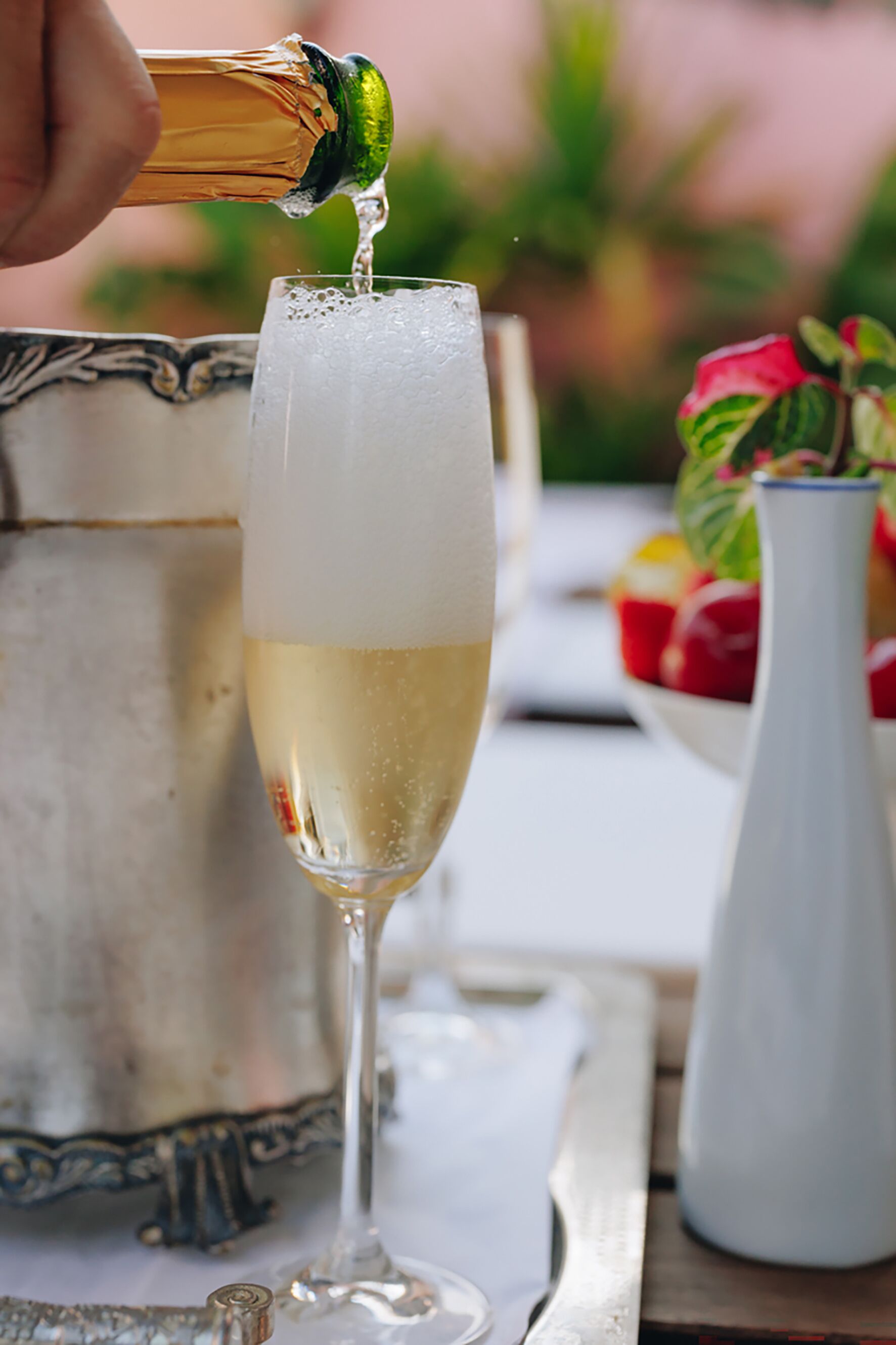 A champagne bottle being poured into a tall glass.
