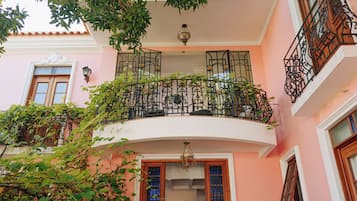 Un edificio rosa con un balcone, una scala e una porta con pannelli di vetro.
