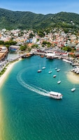 Una cittadina costiera con un porto turistico, barche e una spiaggia.