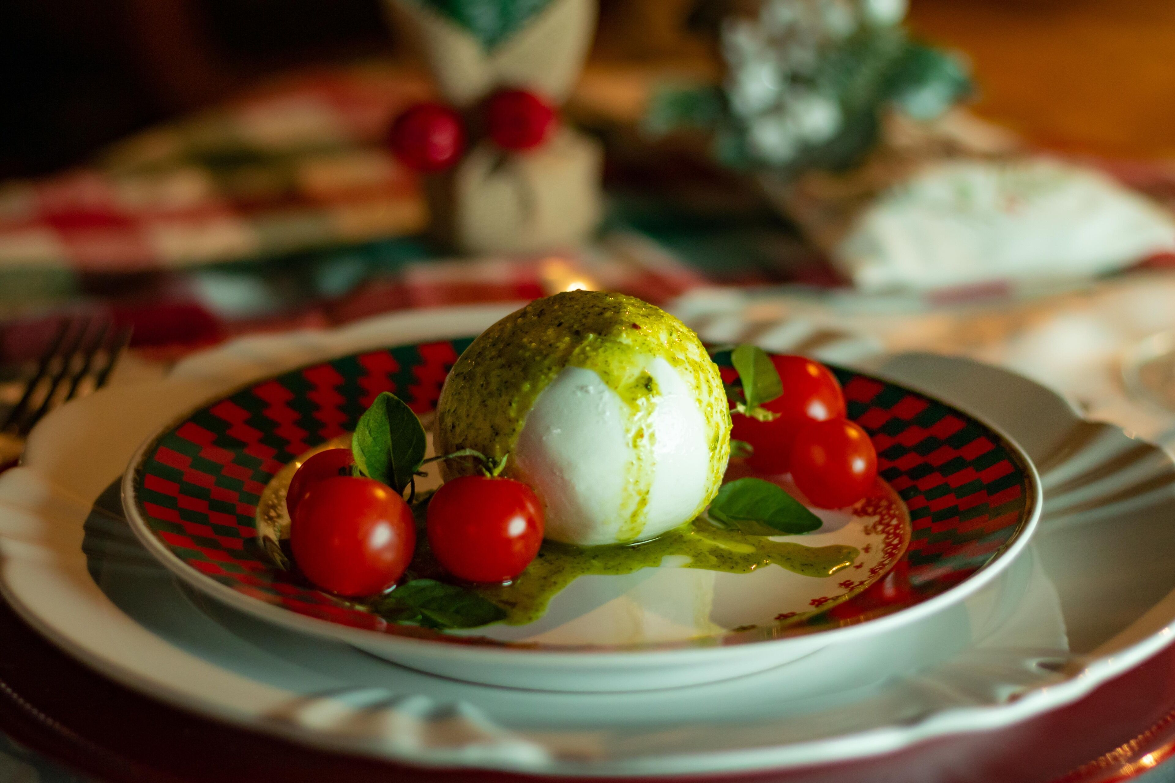 Un plato con un alimento verde y blanco, tomates cherry y una salsa.