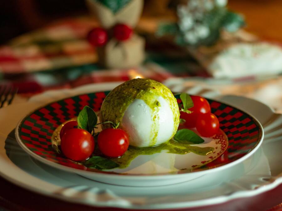 Un plato con un alimento verde y blanco, tomates cherry y una salsa.
