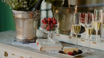 Una mesa con un libro, un cuenco de fresas, un plato de bombones y tres copas de vino blanco.
