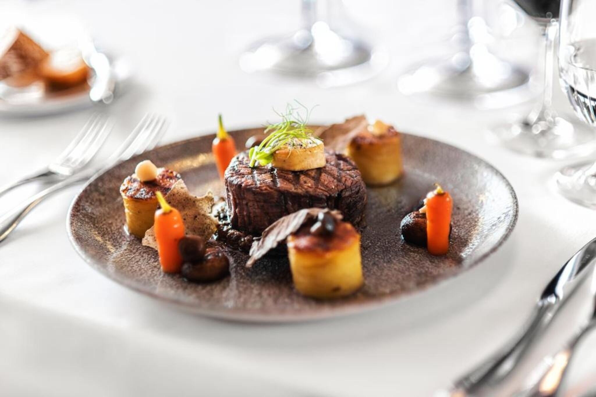 A plate of food with a steak, vegetables, and garnishes.