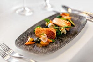 A plate of food with salmon, vegetables, and a small garnish. - Grand Palace Brno - Small Luxury Hotels of the World (Brno)