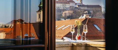 A table with glasses and a vase on a balcony overlooking a historic building.