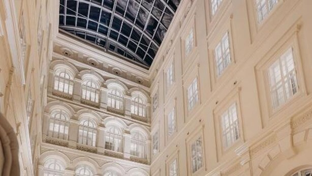 A grand hotel lobby with a high ceiling, multiple floors, and large windows. - Grand Palace Brno - Small Luxury Hotels of the World (Brno)