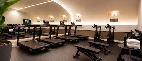 A gym with treadmills, exercise bikes, and dumbbells.