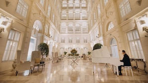 A grand hall with a piano, seating, and a central floral arrangement. - Grand Palace Brno - Small Luxury Hotels of the World (Brno)
