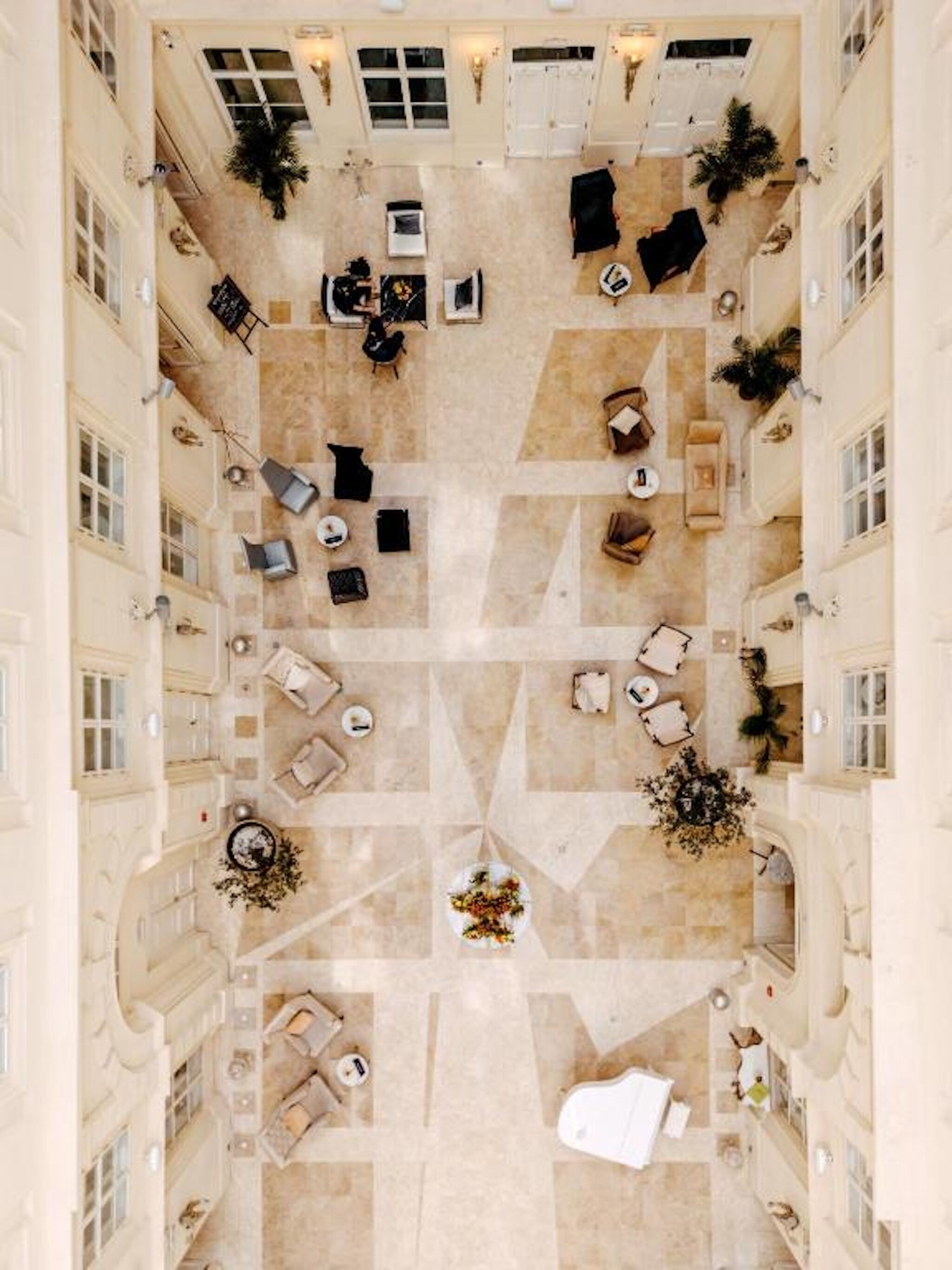 A spacious atrium with multiple seating areas, a central floral arrangement, and a view of the surrounding architecture.