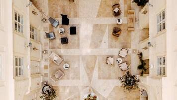 A spacious atrium with multiple seating areas, a central floral arrangement, and a view of the surrounding architecture.