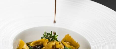 A hand pouring sauce over a dish of pasta.