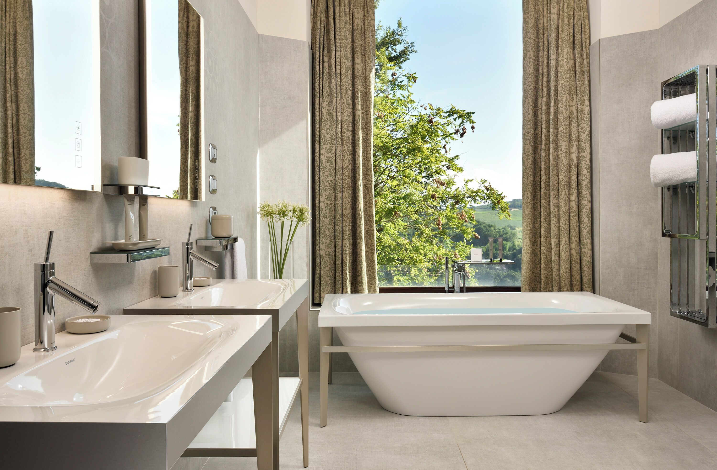 Une salle de bain moderne avec deux vasques, une baignoire sur pieds et une grande fenêtre avec des rideaux.