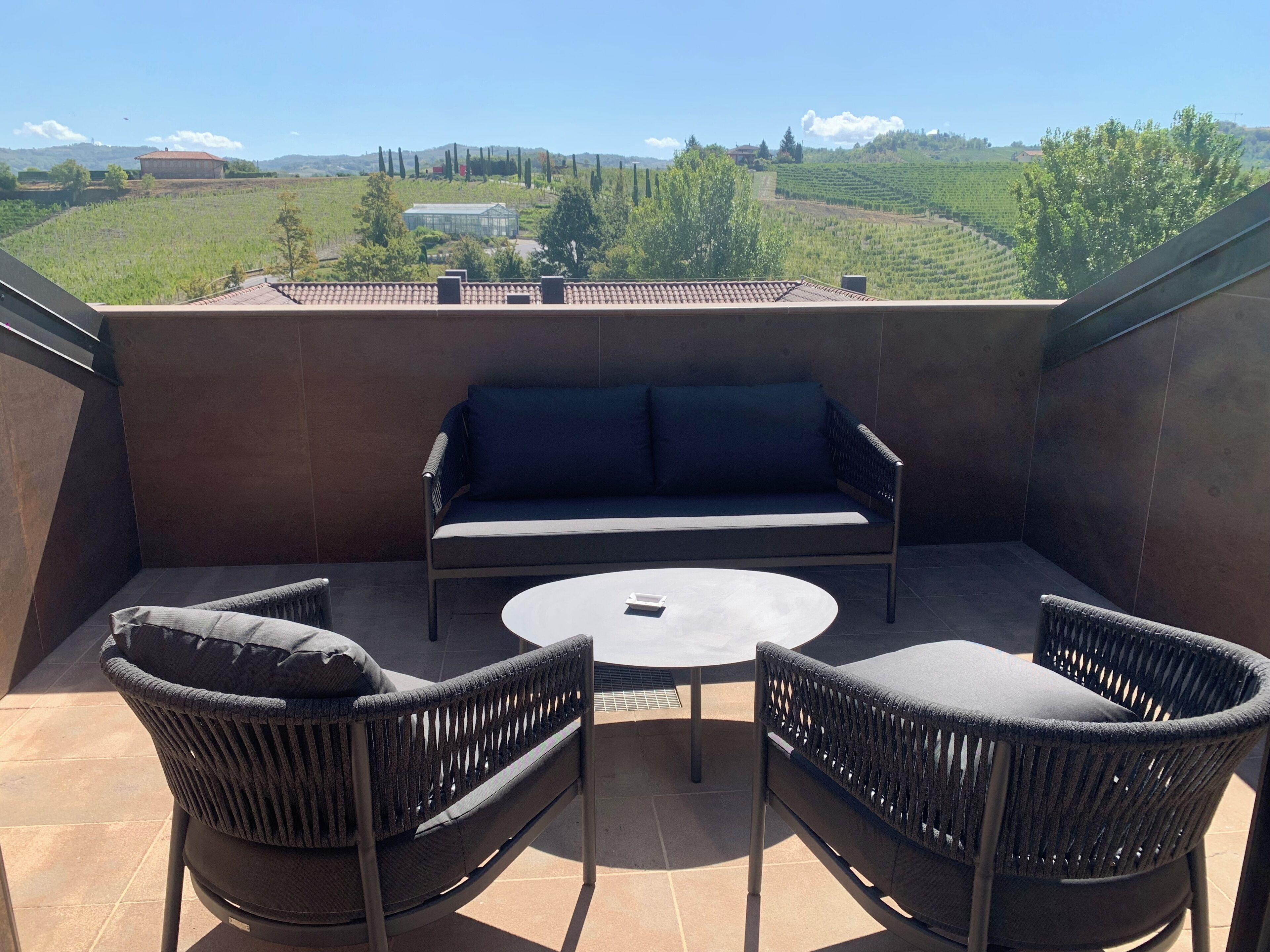 Una terraza con un sofá, dos sillas y una mesa.