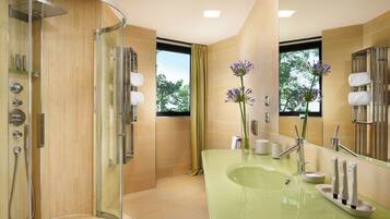 Un baño moderno con ducha de vidrio, un lavamanos verde y un espejo grande.