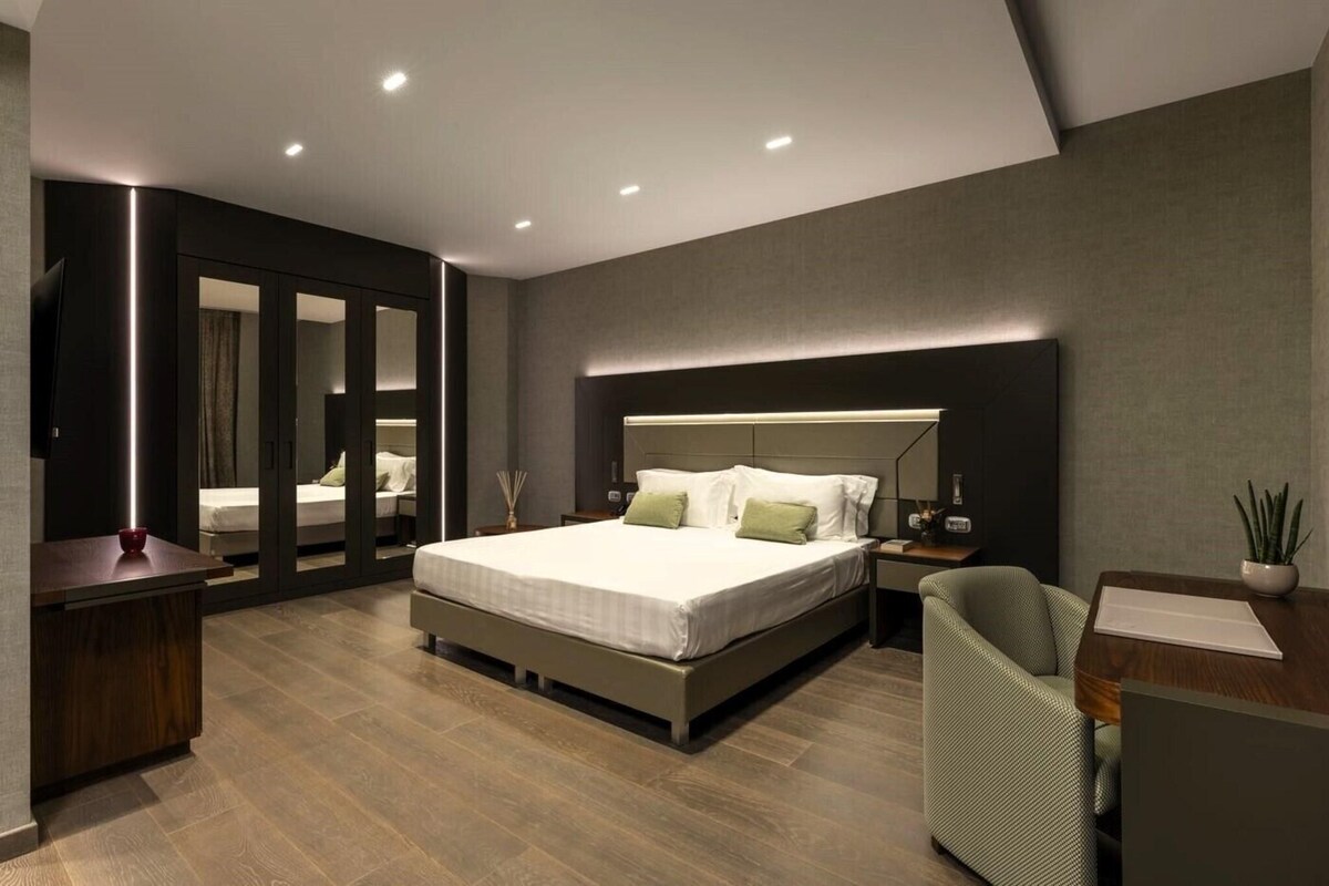 Un dormitorio moderno con una cama grande, mesitas de noche, un escritorio y una silla.
