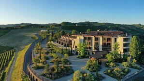 A modern building with a curved driveway, surrounded by landscaped gardens and vineyards. - Il Boscareto Resort & Spa (Serralunga d'Alba)