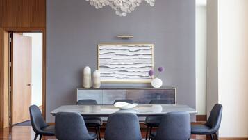 Un comedor moderno con pared gris, un cuadro abstracto grande y una puerta de madera.