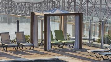 Area piscina con sedie a sdraio e un gazebo che si affaccia su un ponte.