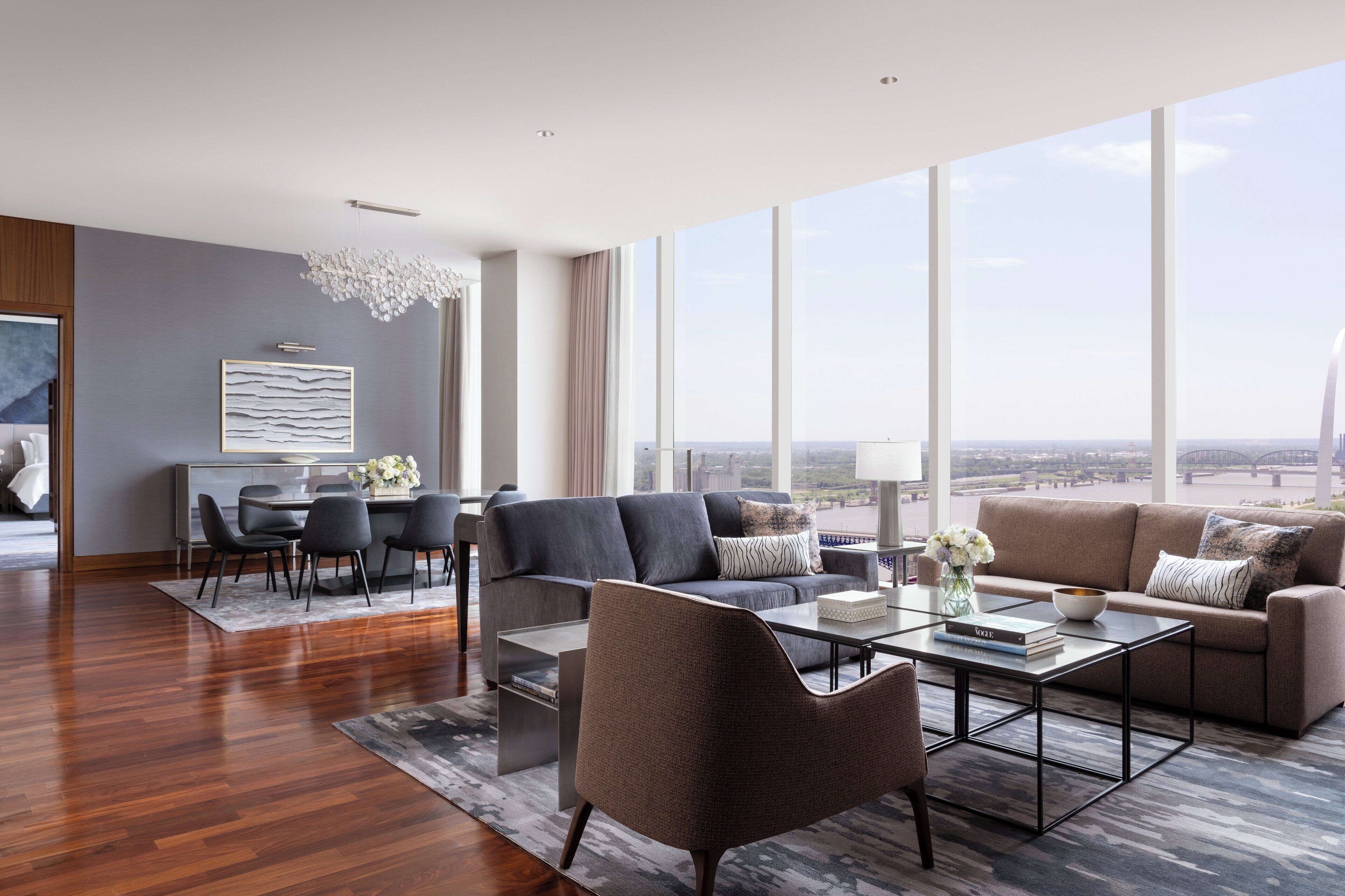 A spacious living room with a modern sofa, a coffee table, and a dining area with chairs and a table.