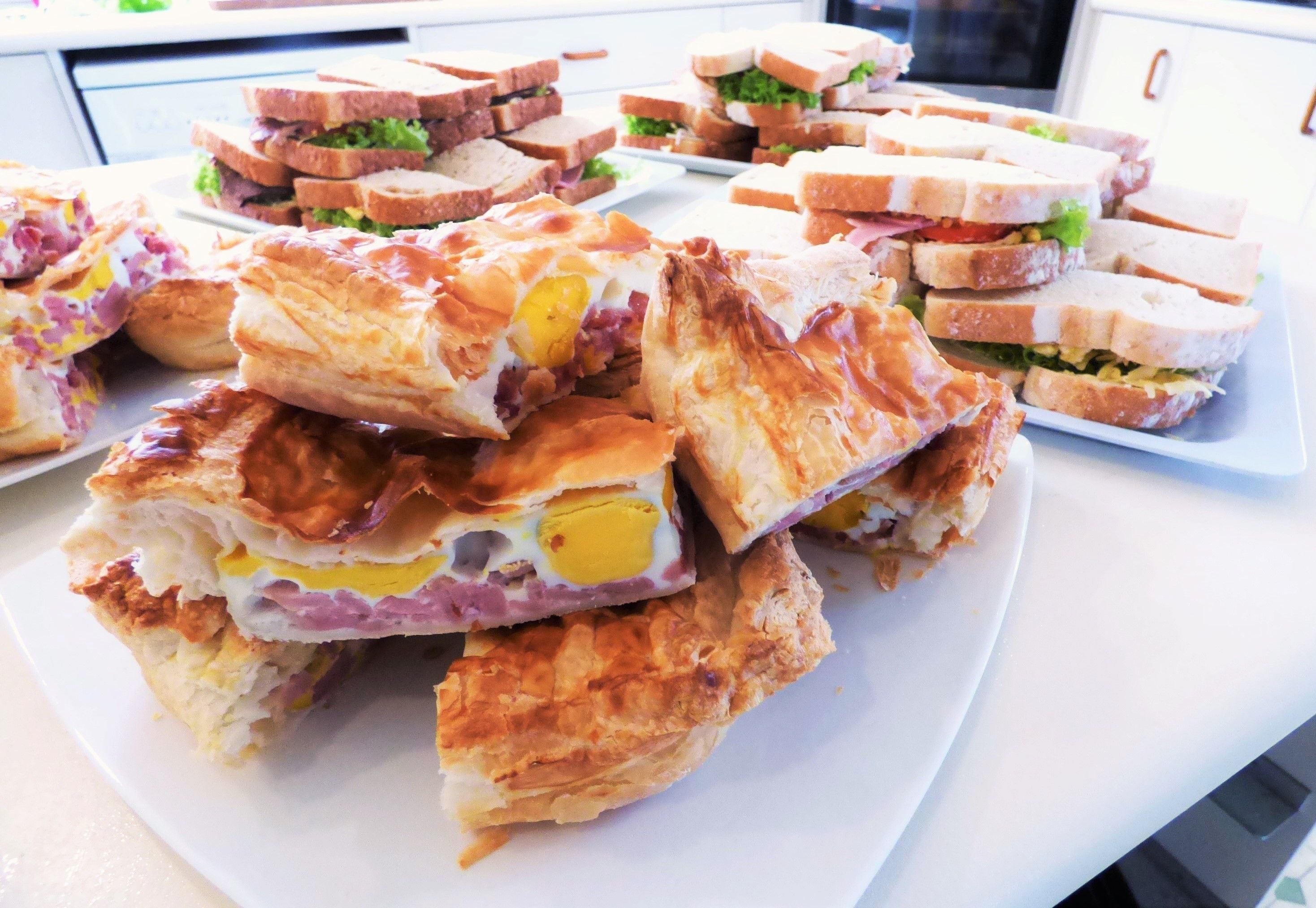 A variety of sandwiches on a white plate, including some with egg and ham.