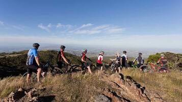 Un grupo de ciclistas de montaña en un sendero, con una vista de una ciudad al fondo.