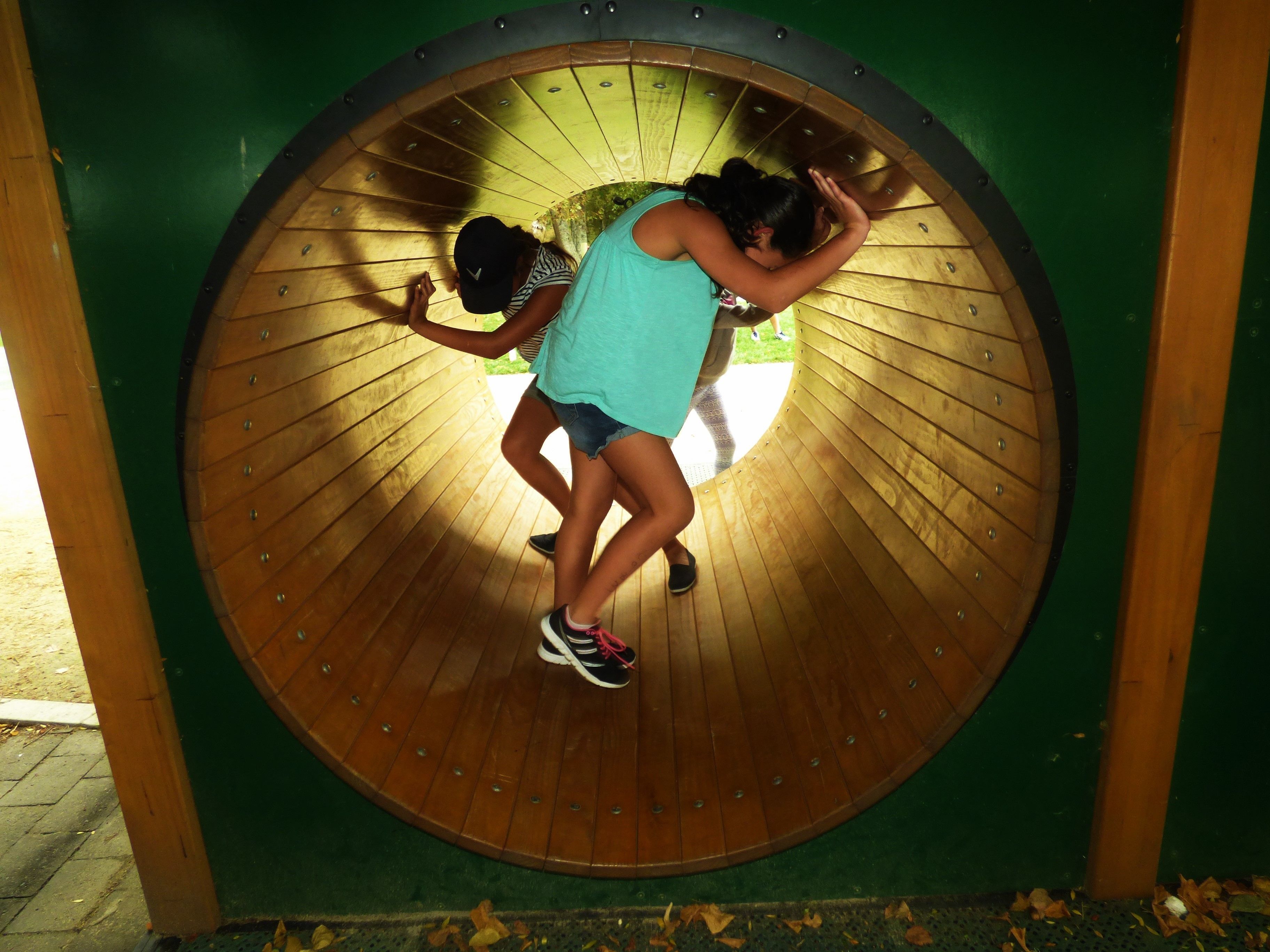 A circular wooden structure with a green exterior, possibly a play area or tunnel.