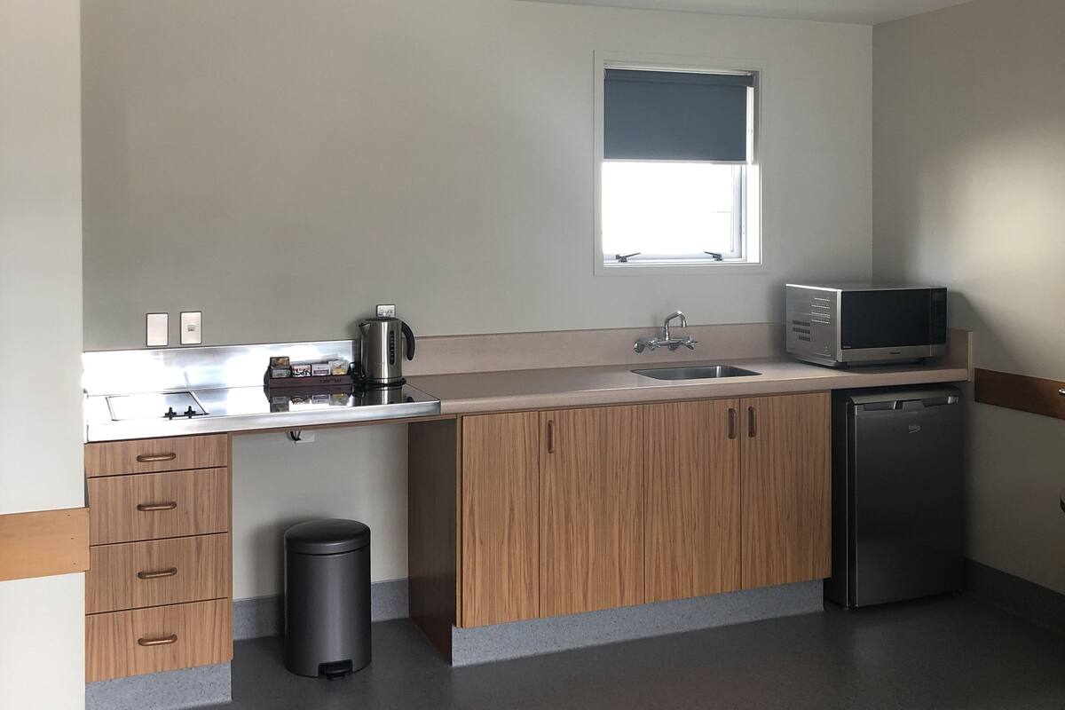 A modern kitchen with a built-in oven, microwave, sink, and wooden cabinets.