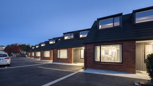 A row of modern houses with large windows and a parking lot in front. - Dunedin Motel and Villas (Dunedin)