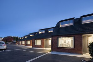A row of modern houses with large windows and a parking lot in front. - Dunedin Motel and Villas (Dunedin)