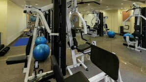 A gym with exercise equipment, mirrors, and blue exercise balls. - Savoy Suites (Noida)