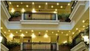 A multi-level hotel lobby with a central seating area, a TV screen, and multiple balconies. - Savoy Suites (Noida)