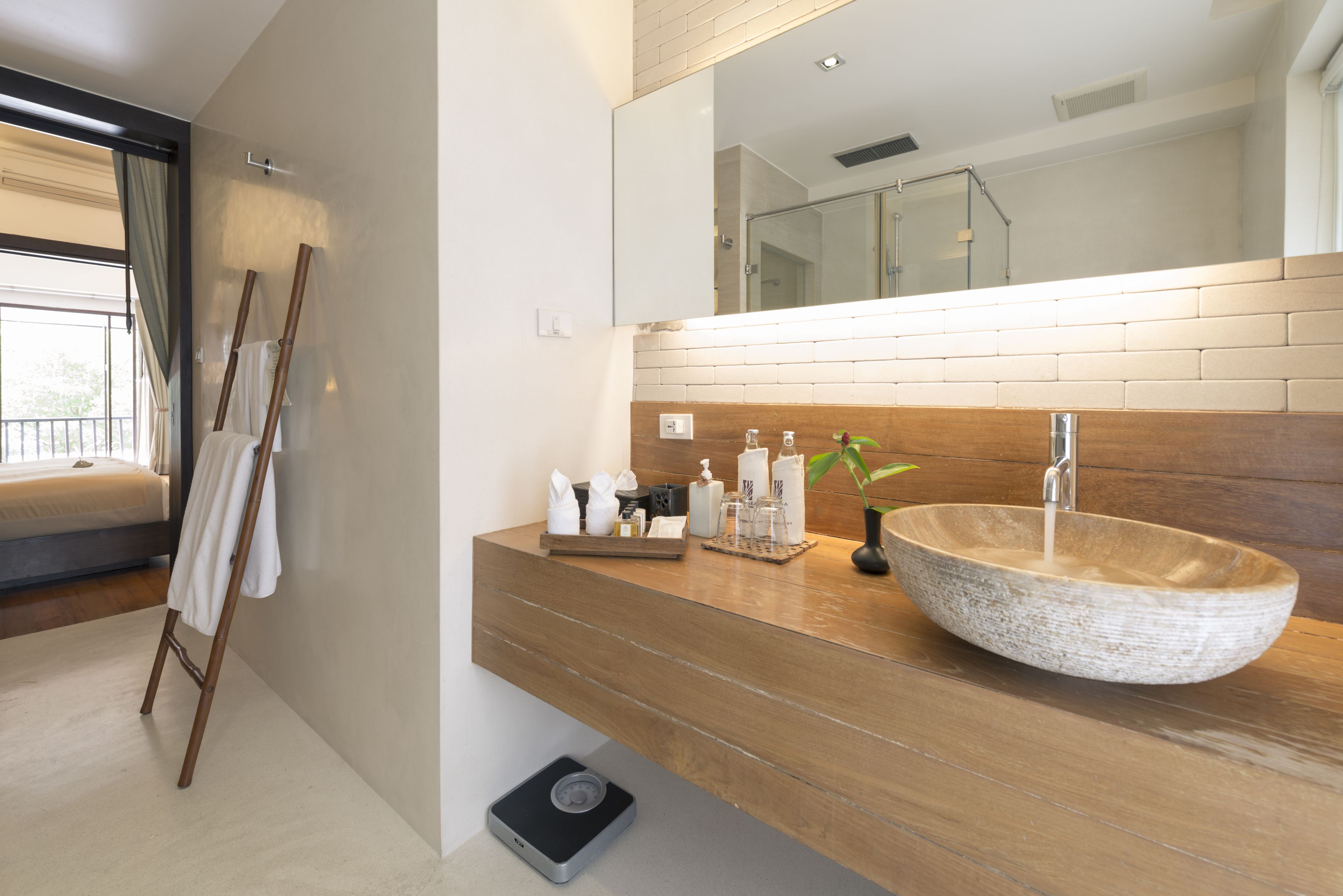 Un baño moderno con tocador de madera, un espejo grande y un lavamanos de piedra.
