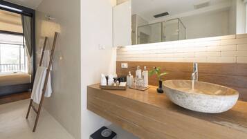 Un baño moderno con tocador de madera, un espejo grande y un lavamanos de piedra.