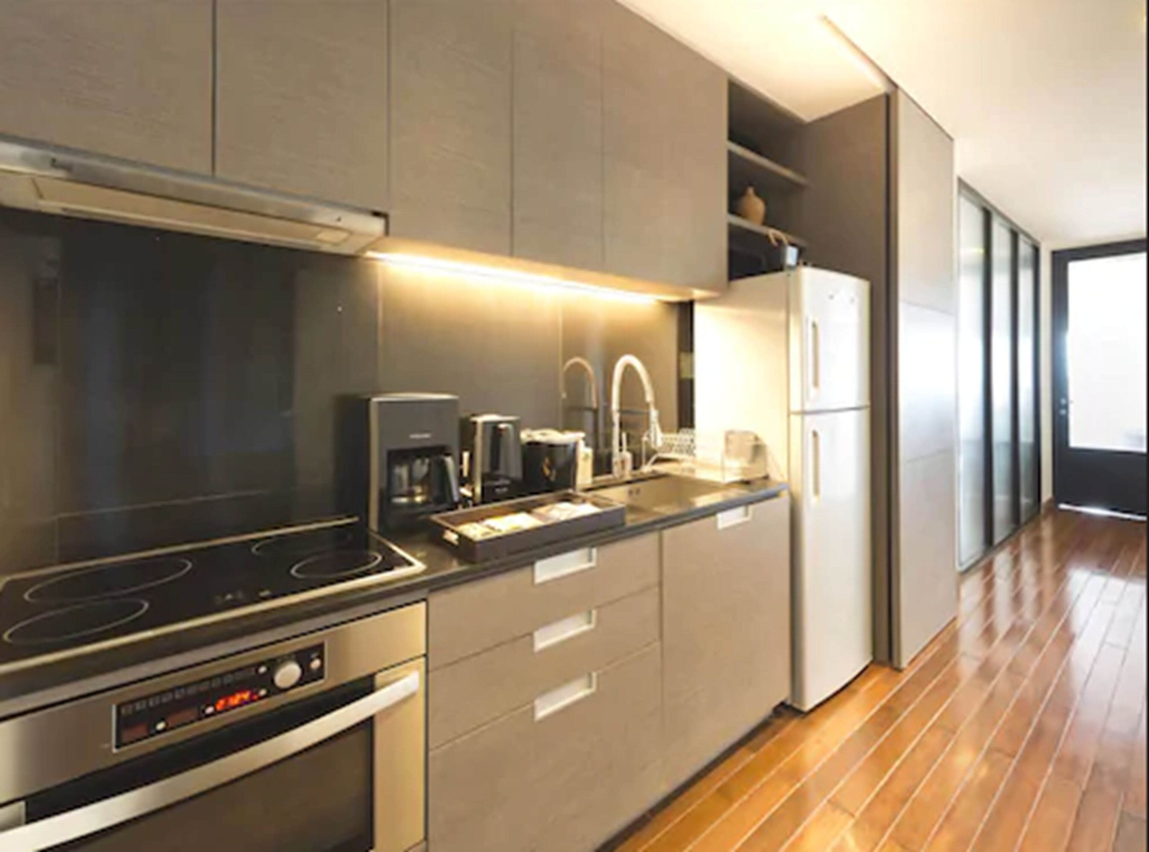 A modern kitchen with a built-in oven, a coffee maker, and a refrigerator.