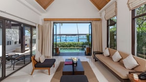 A modern living room with a sofa, a coffee table, and a chair. There is a large window with a view of the sea. - The Sea Koh Samui Resort & Residences by Tolani (Koh Samui)