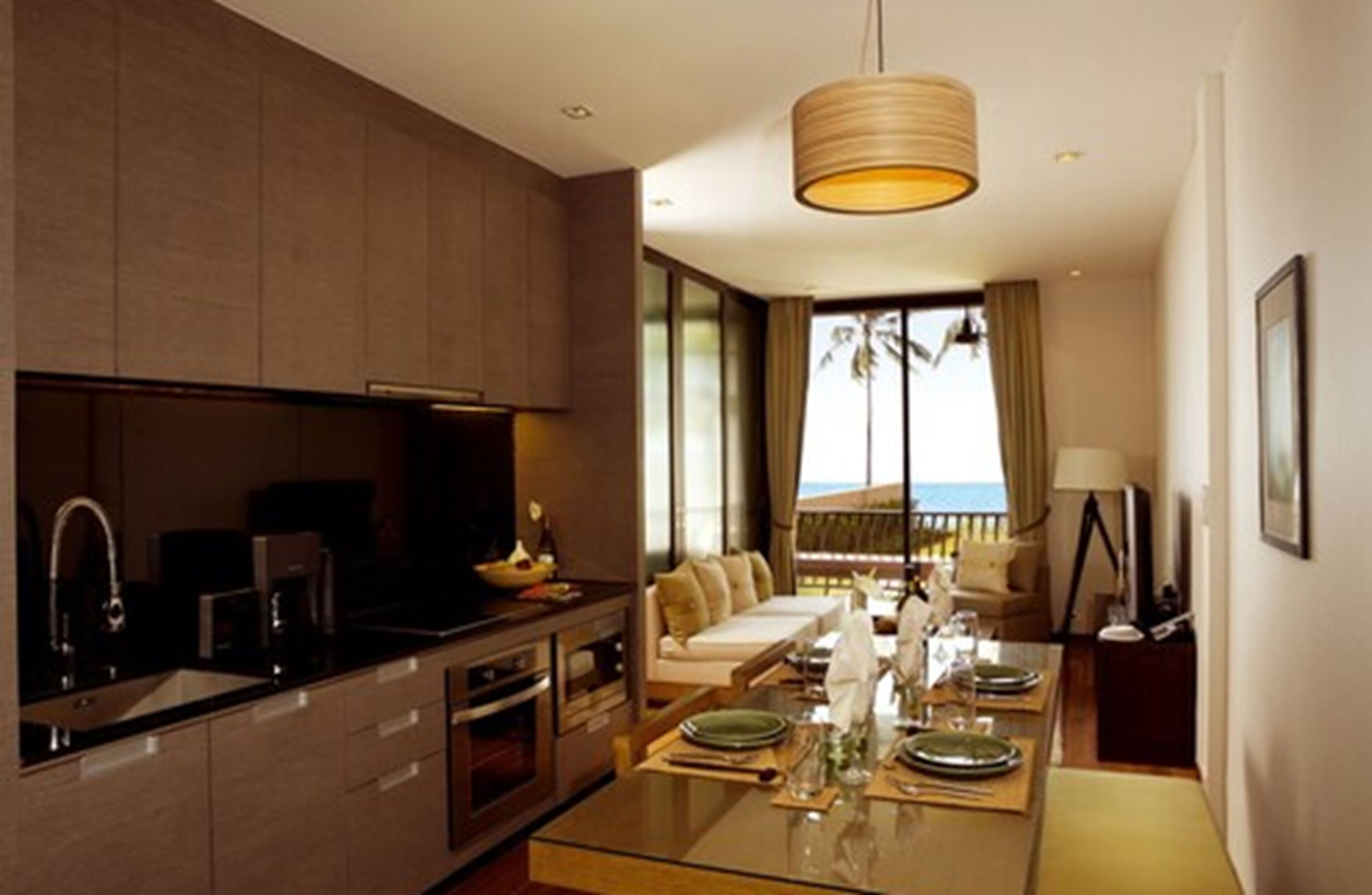 A modern kitchen with a dining area, large windows, and a view of the ocean.