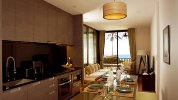 A modern kitchen with a dining area, large windows, and a view of the ocean.