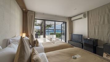 Habitación de hotel con dos camas, televisión y balcón con vista al mar.