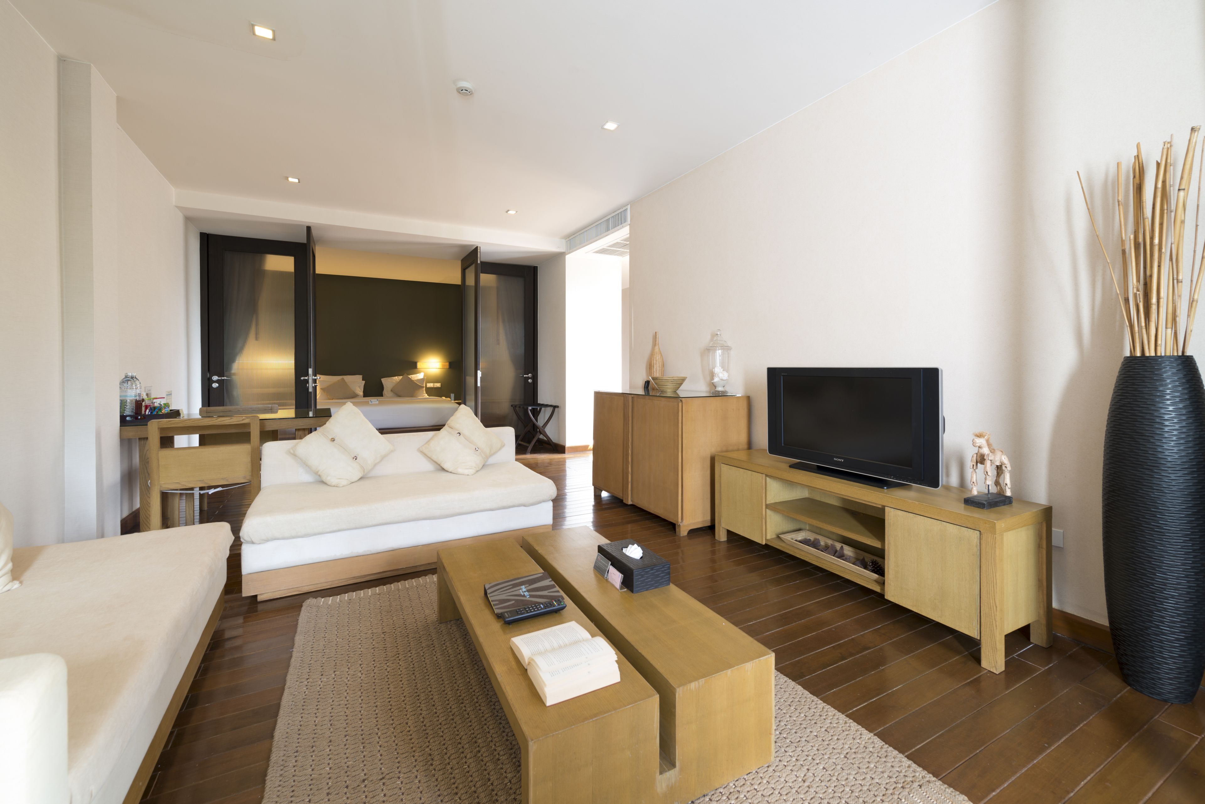 Una sala de estar moderna con un sofá, una mesa de centro, un mueble para televisor y un jarrón grande.